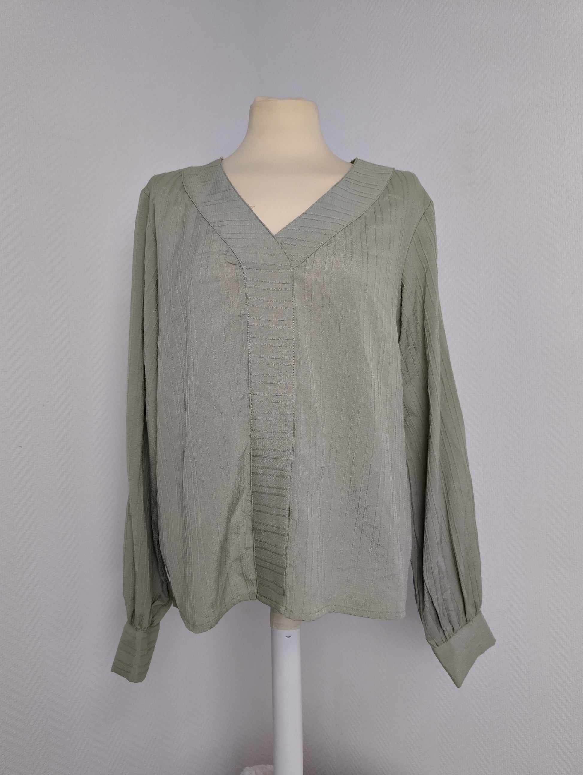 Front view of green long-sleeve blouse on mannequin