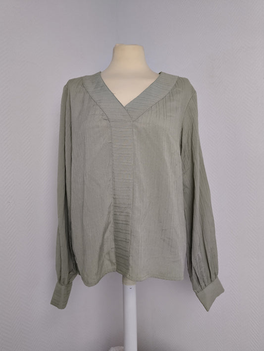 Front view of green long-sleeve blouse on mannequin