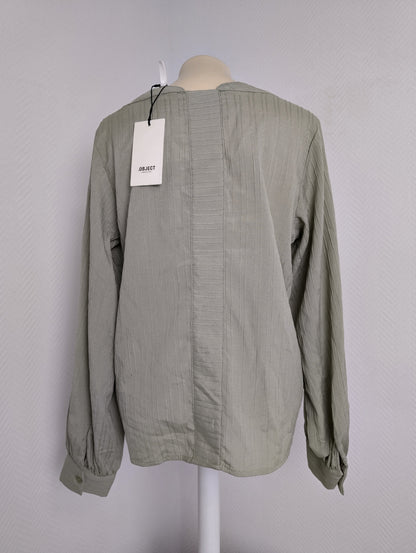 Back view of green long-sleeve blouse with tag
