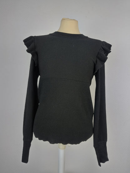 Front view of black ribbed knit top with ruffle shoulders