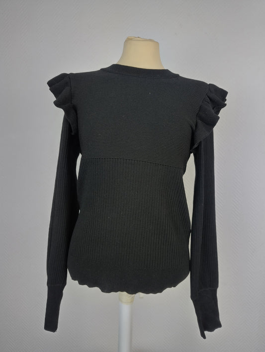 Front view of black ribbed knit top with ruffle shoulders