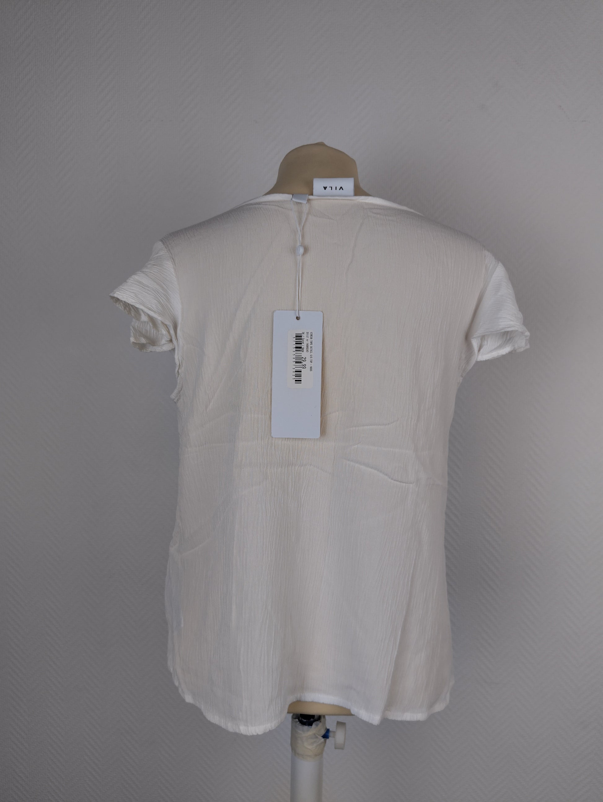 Back view of white textured blouse with tag