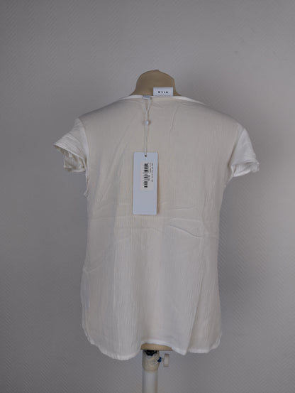 Back view of white textured blouse with tag