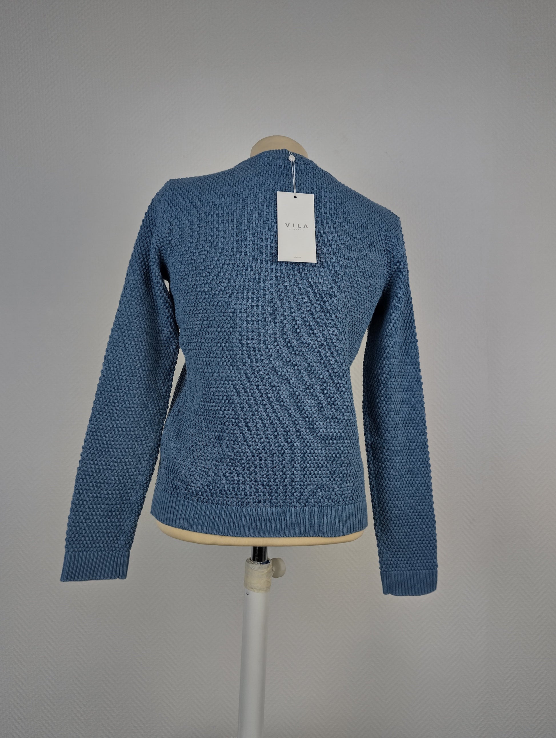 Back view of blue textured knit sweater with tag on mannequin