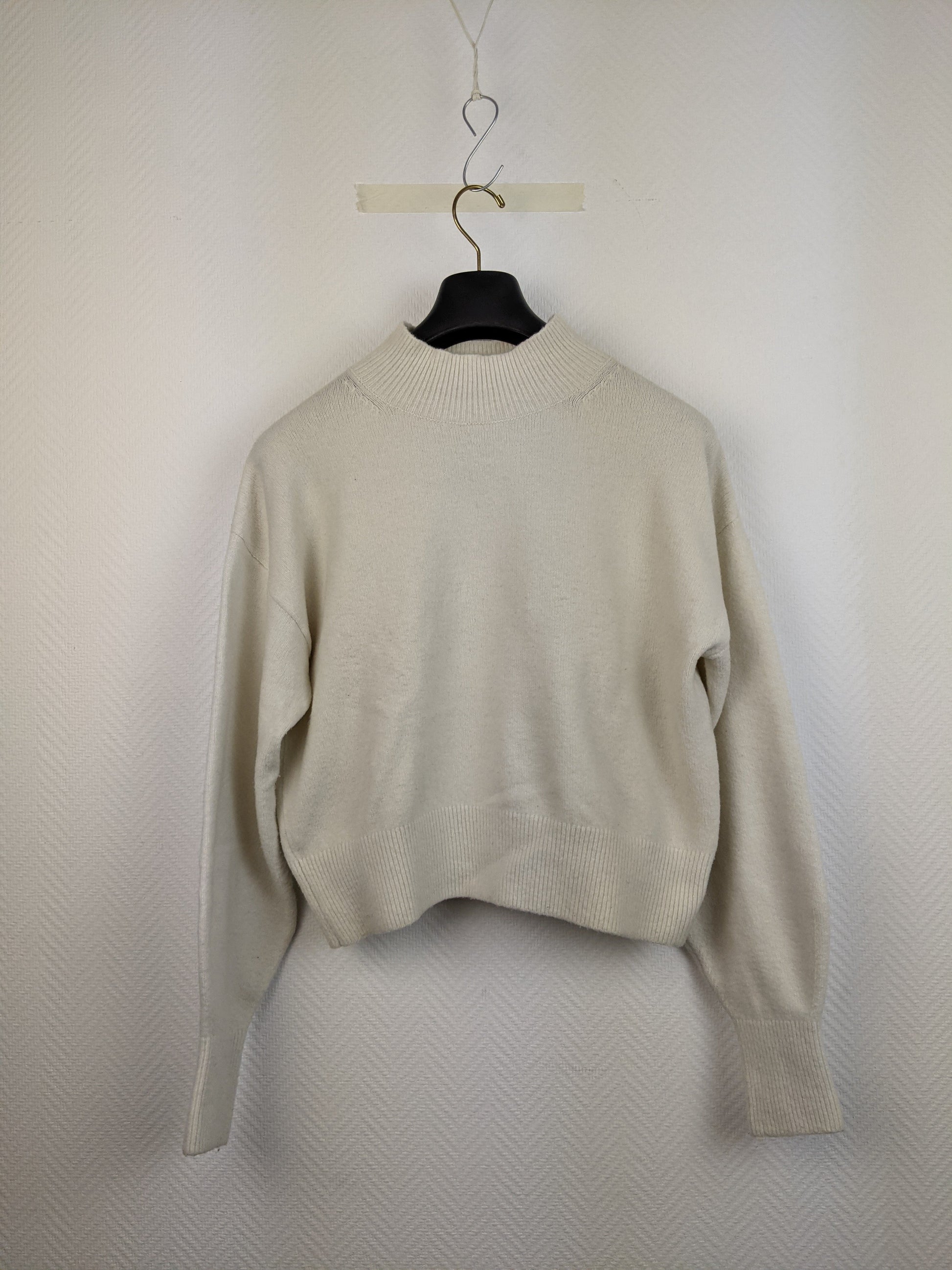 Front view of cream knit sweater on hanger