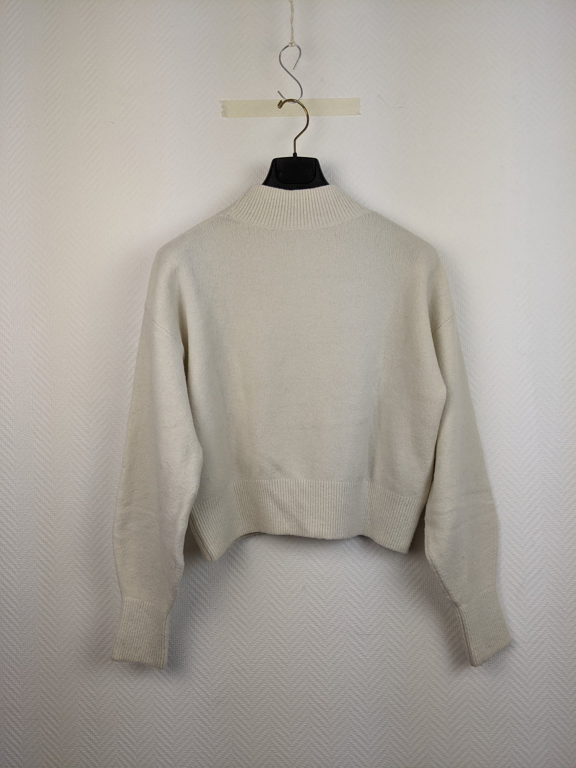 Back view of cream knit sweater on hanger