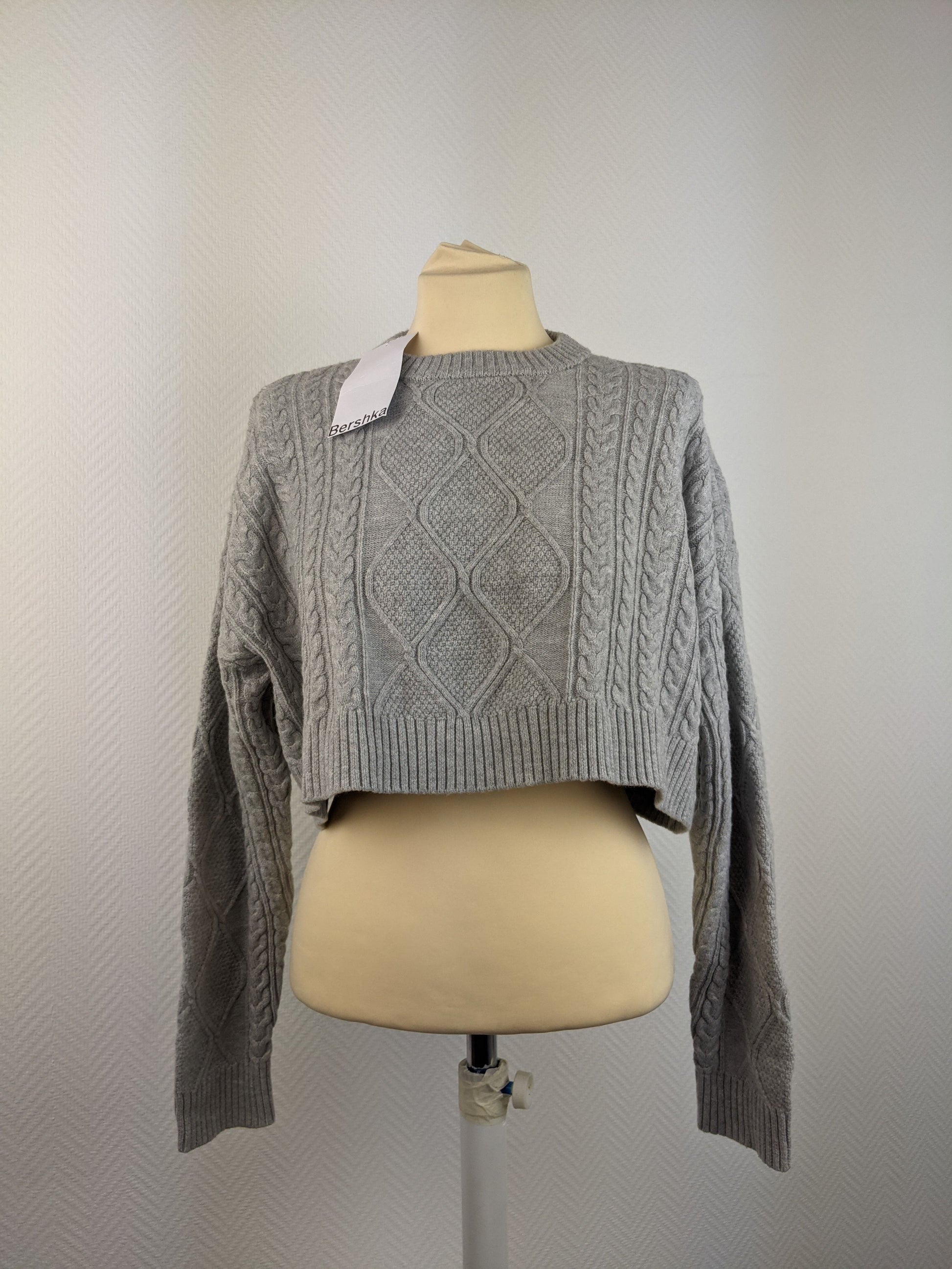Front view of grey cable knit sweater on mannequin