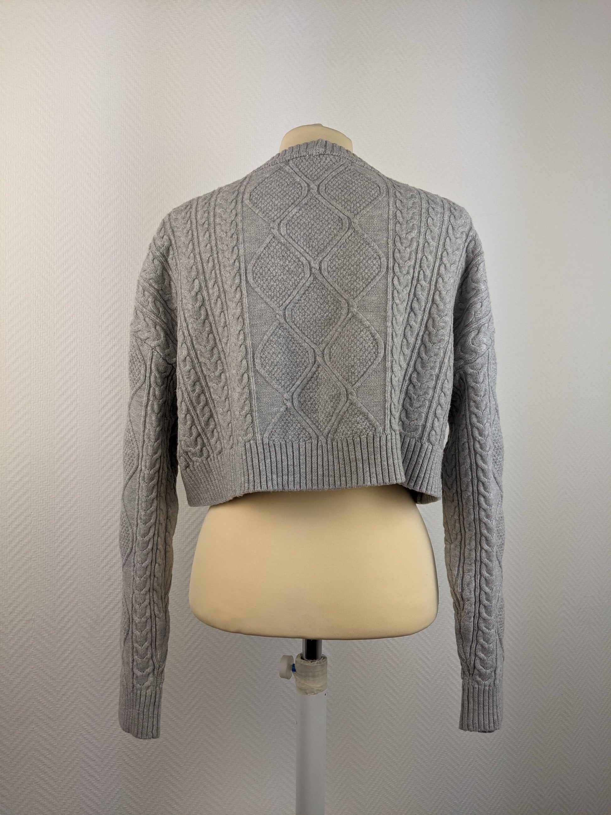 Back view of grey cable knit sweater on mannequin