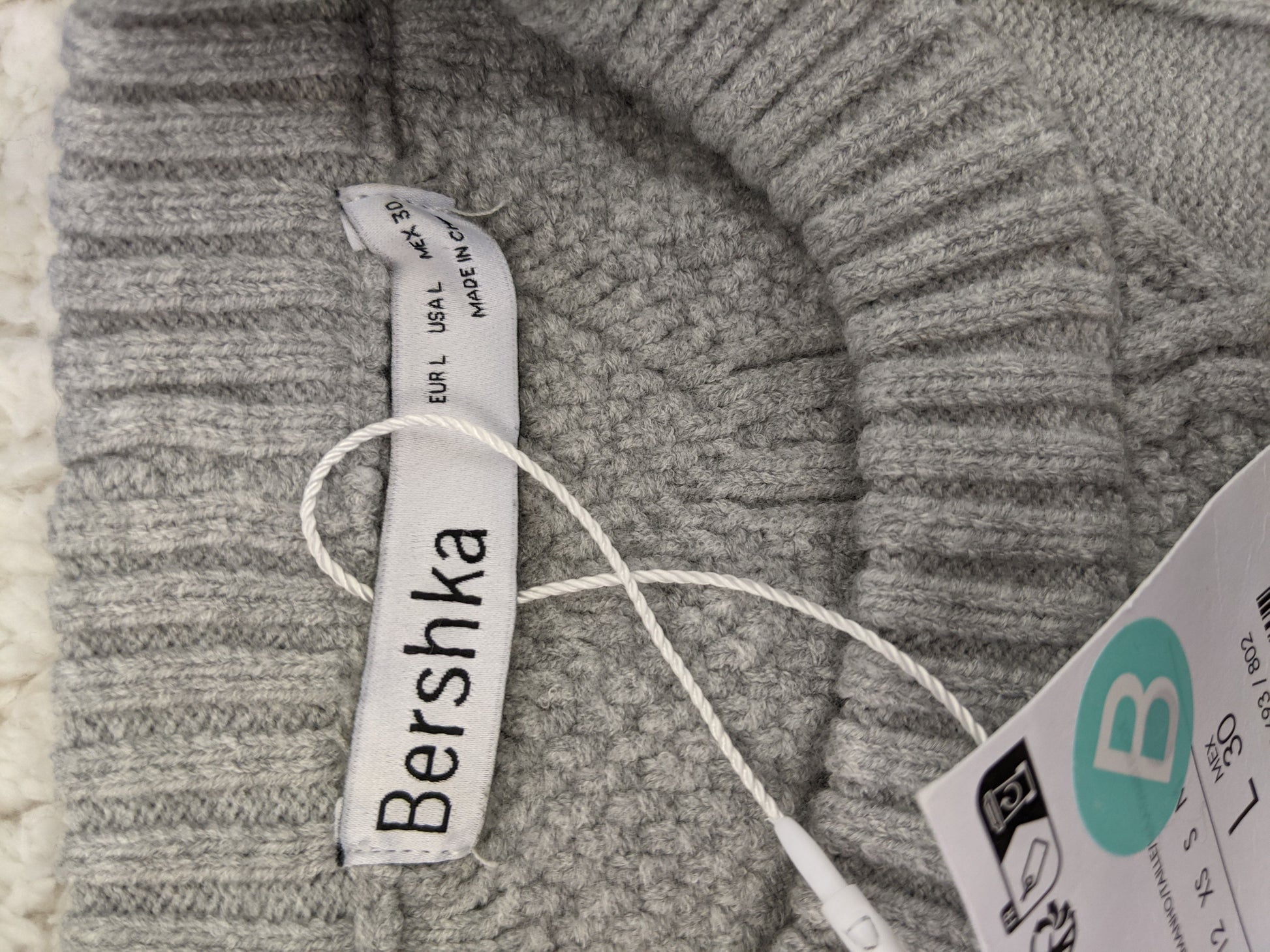 Close-up of Bershka label and tags on grey sweater