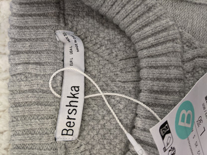 Close-up of Bershka label and tags on grey sweater
