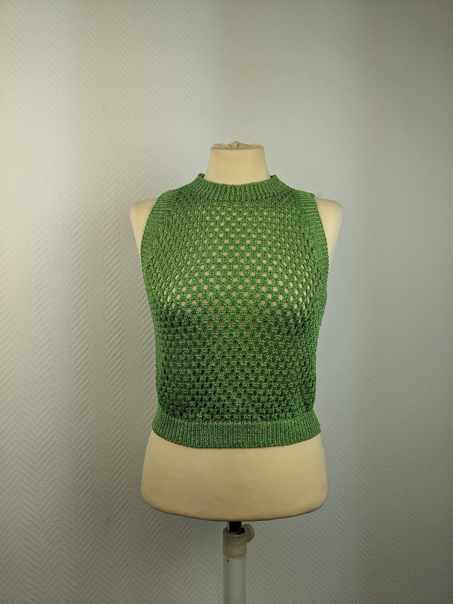 Front view of green crochet sleeveless top on a mannequin