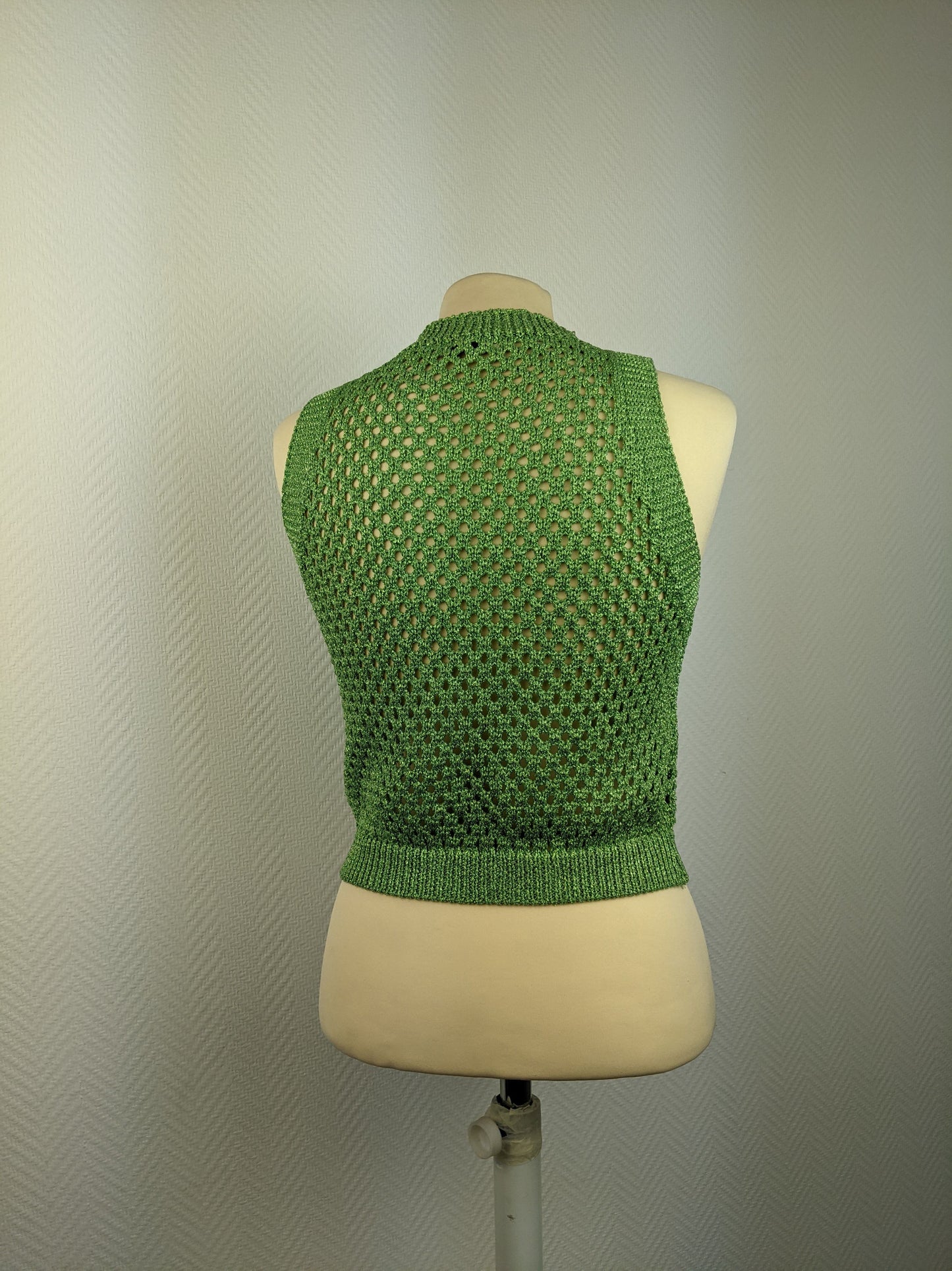Back view of green crochet sleeveless top on a mannequin