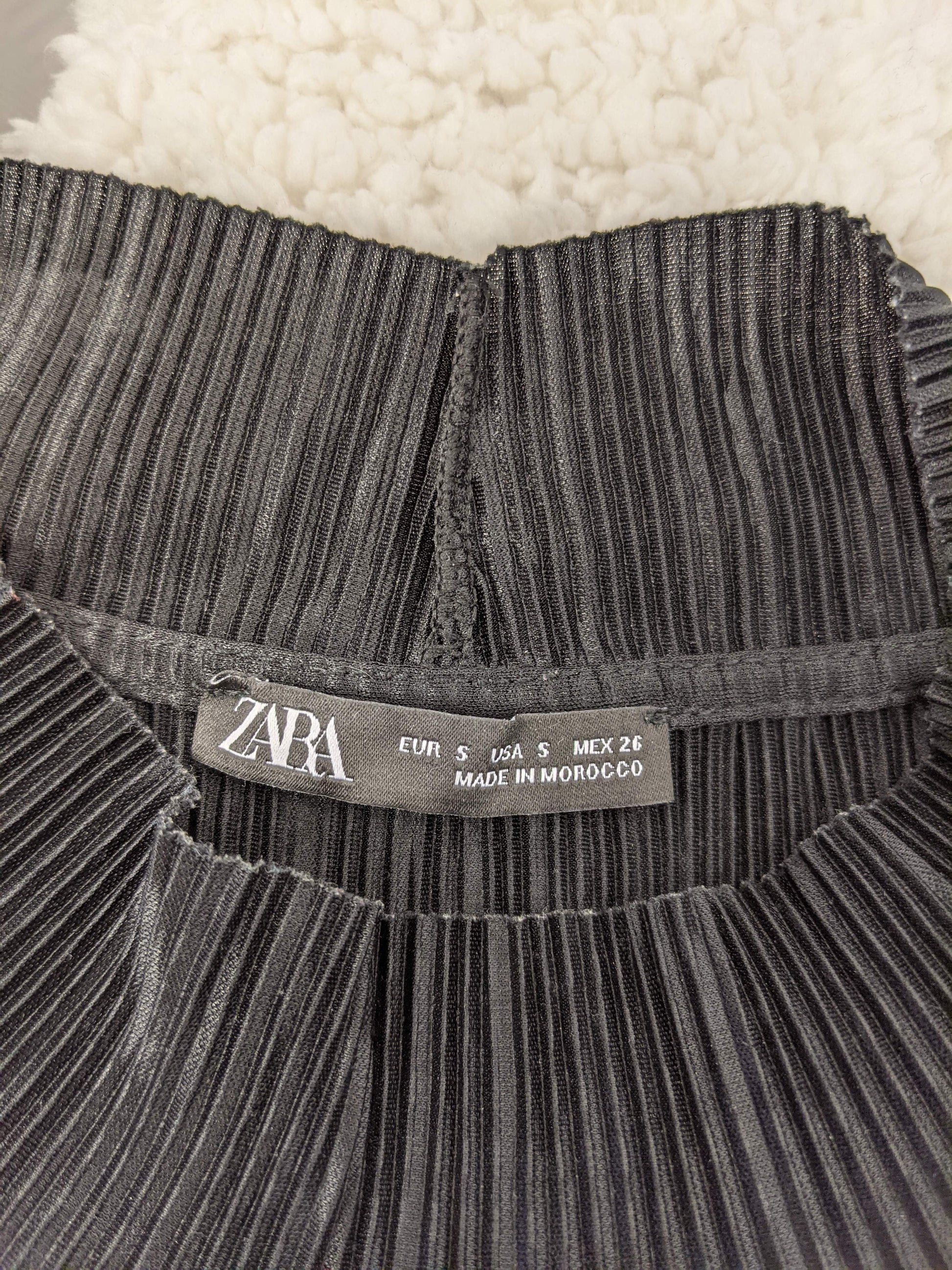 Close-up of Zara label on black pleated top