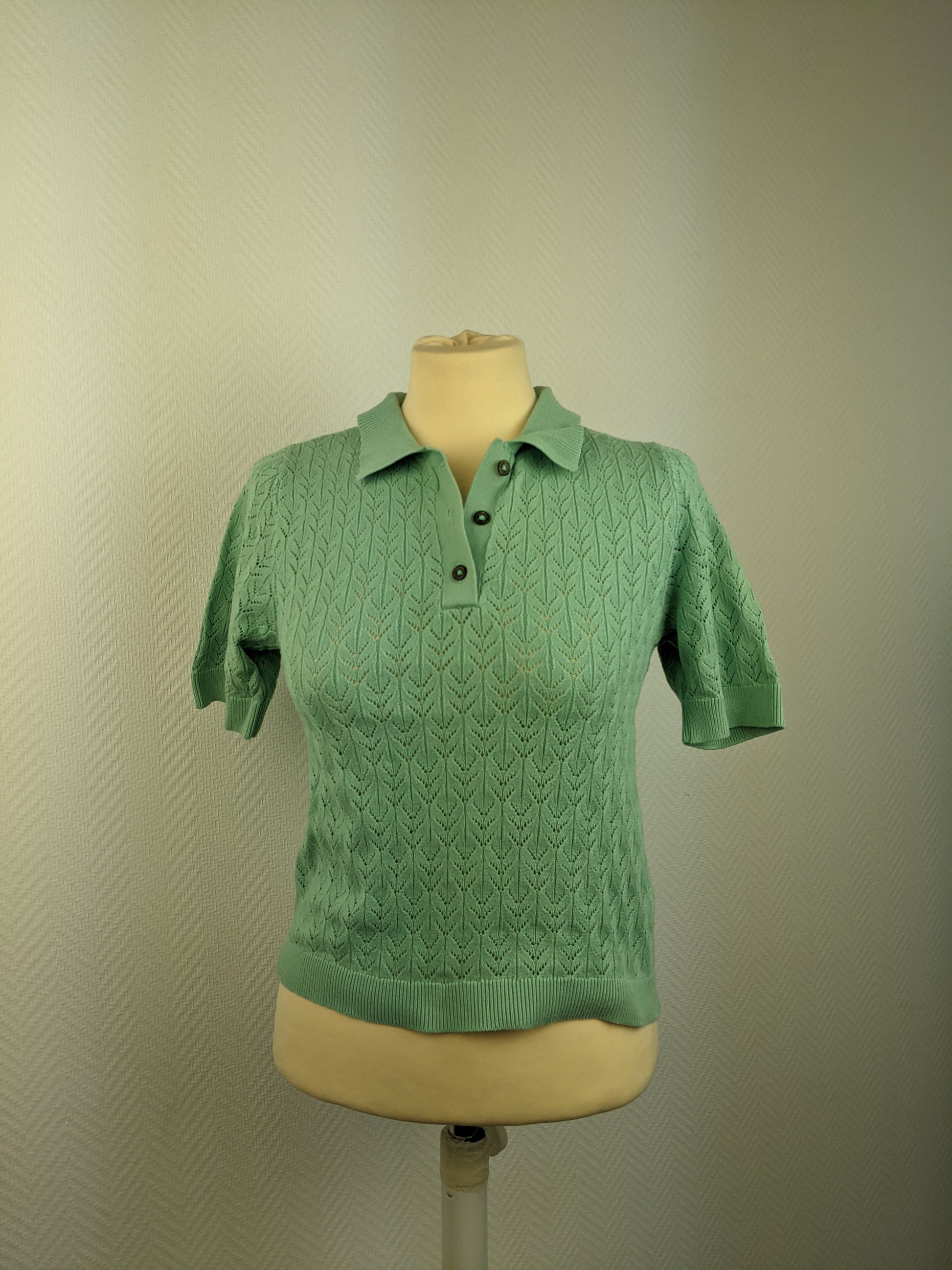 Front view of green knit polo shirt on mannequin