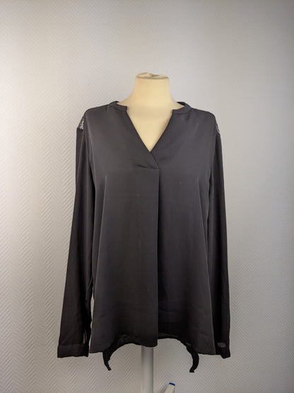 Black blouse with lace details at the back hanging on a mannequin