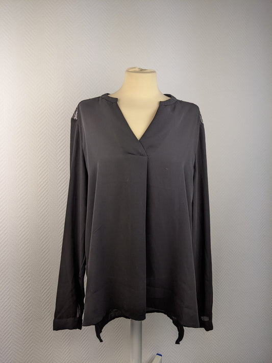 Black blouse with lace details at the back hanging on a mannequin