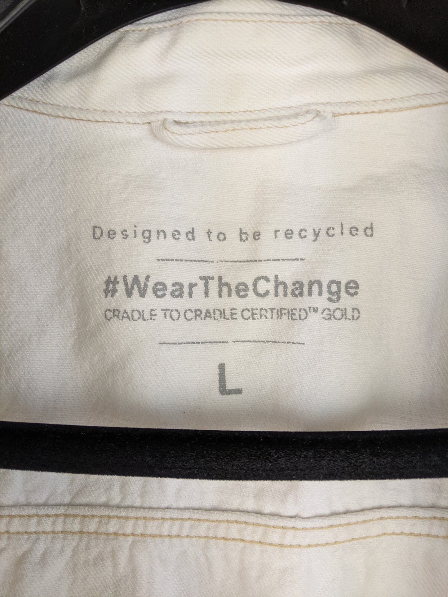 Label of white sustainable denim jacket showing recycling design and size L