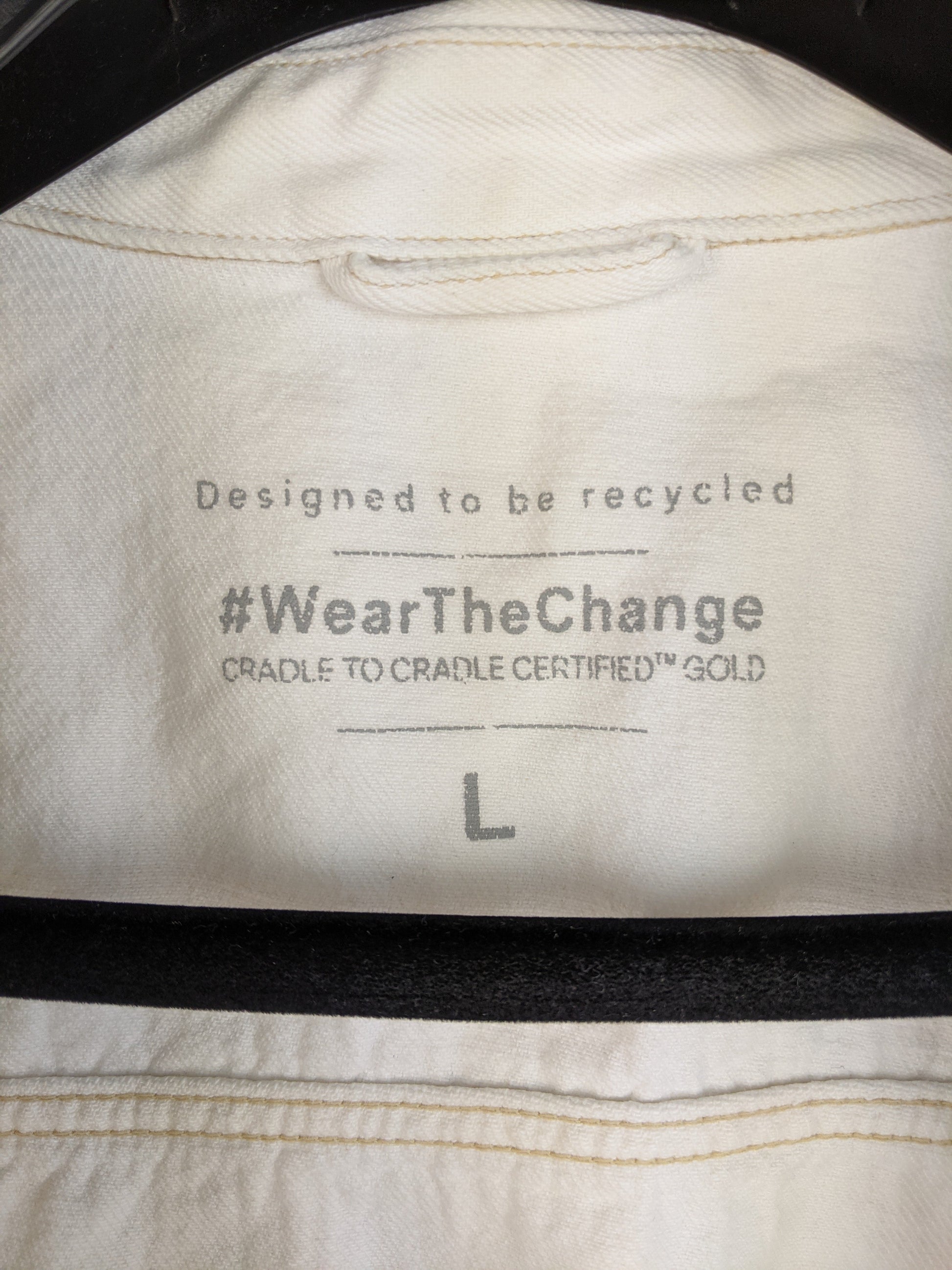 Label of white sustainable denim jacket showing recycling design and size L