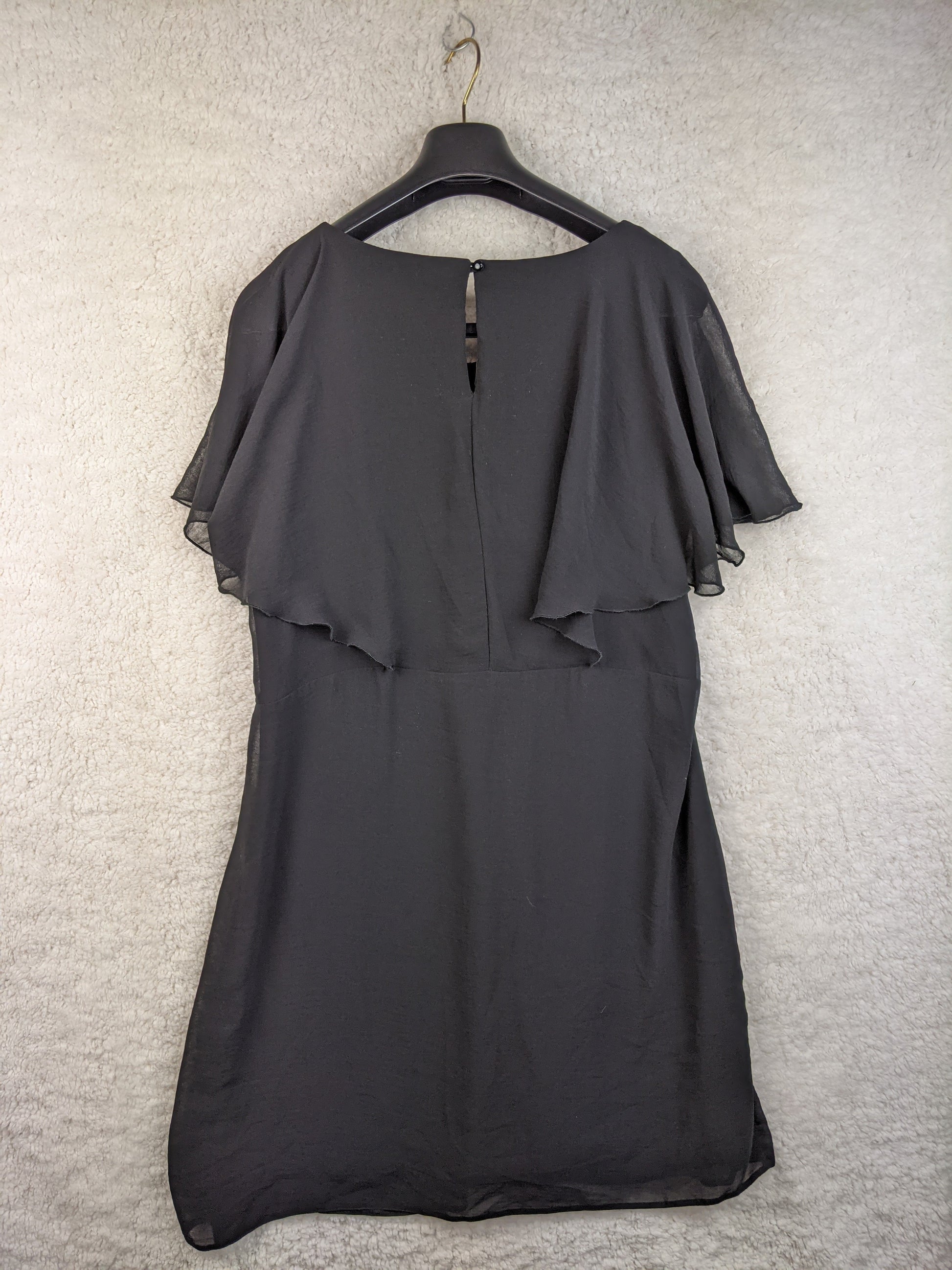 Back view of black chiffon dress on hanger