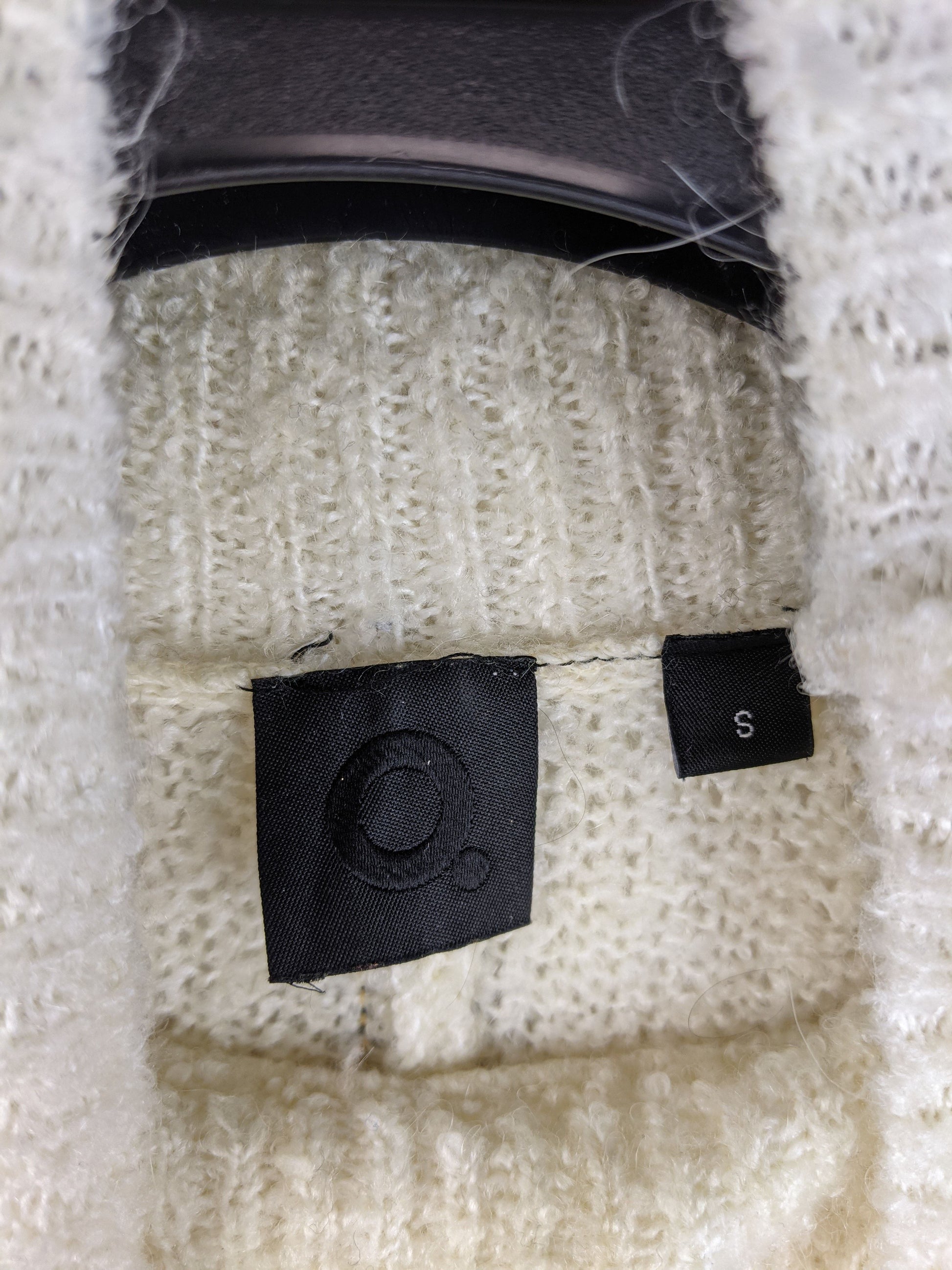 Close-up of label inside cream high neck sweater