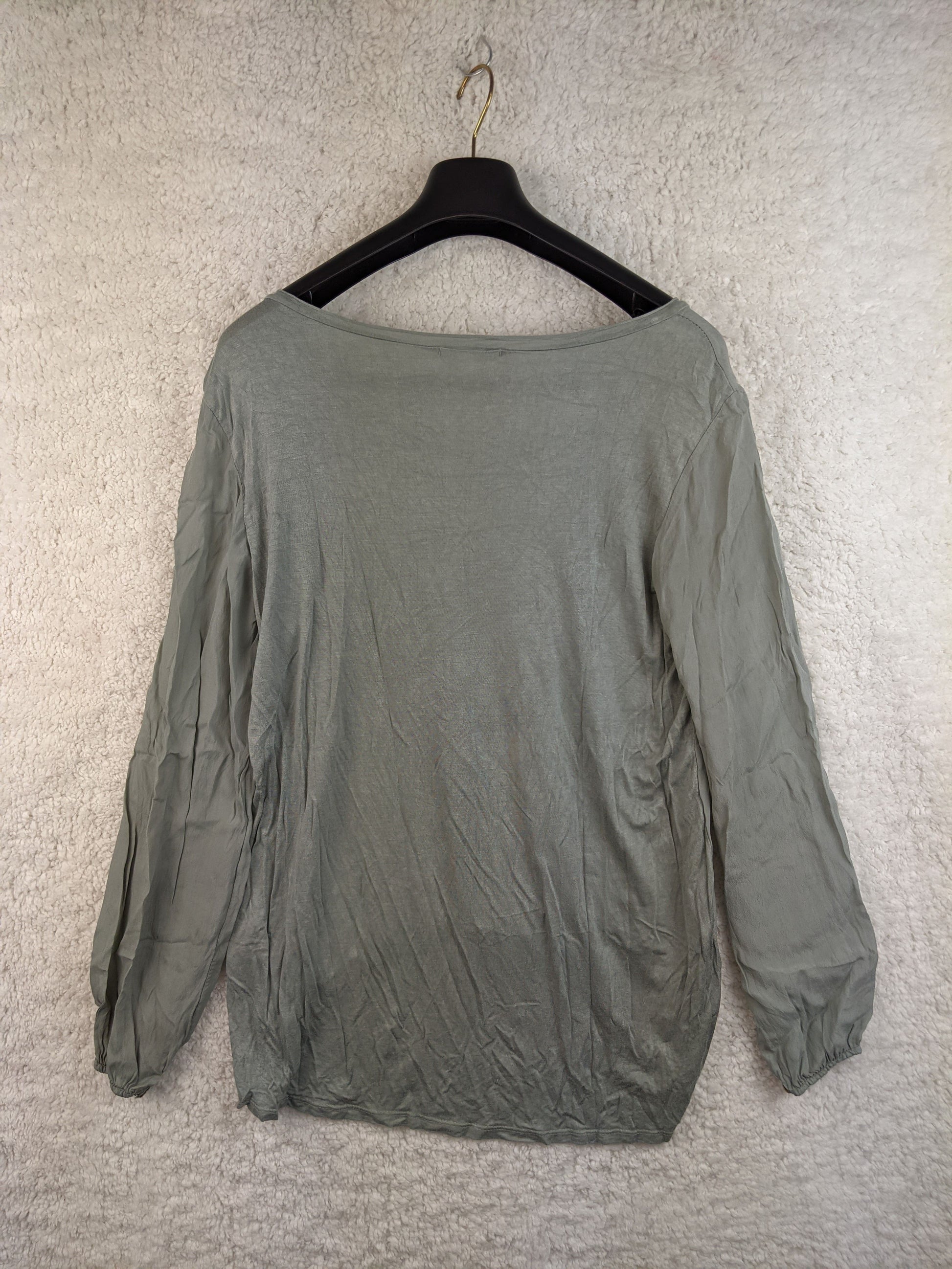 Back view of sage green blouse on hanger