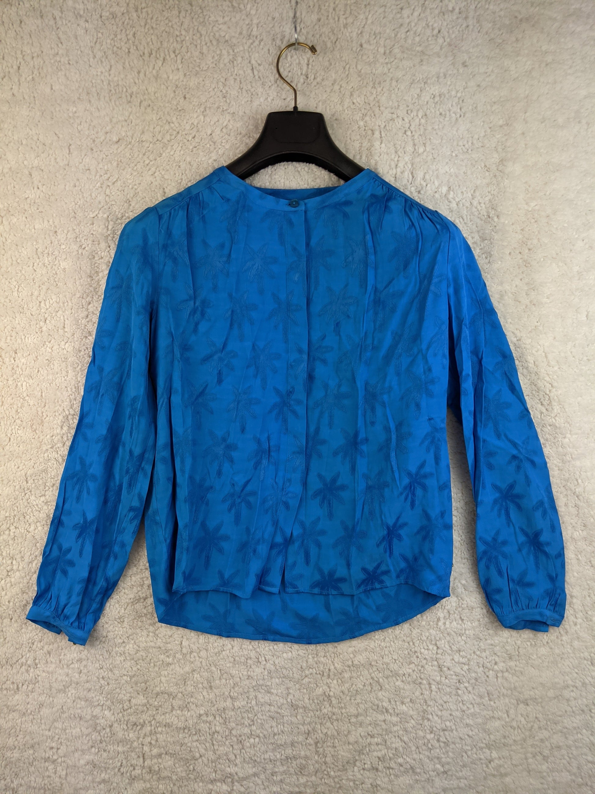 Blue floral blouse on a hanger - front view