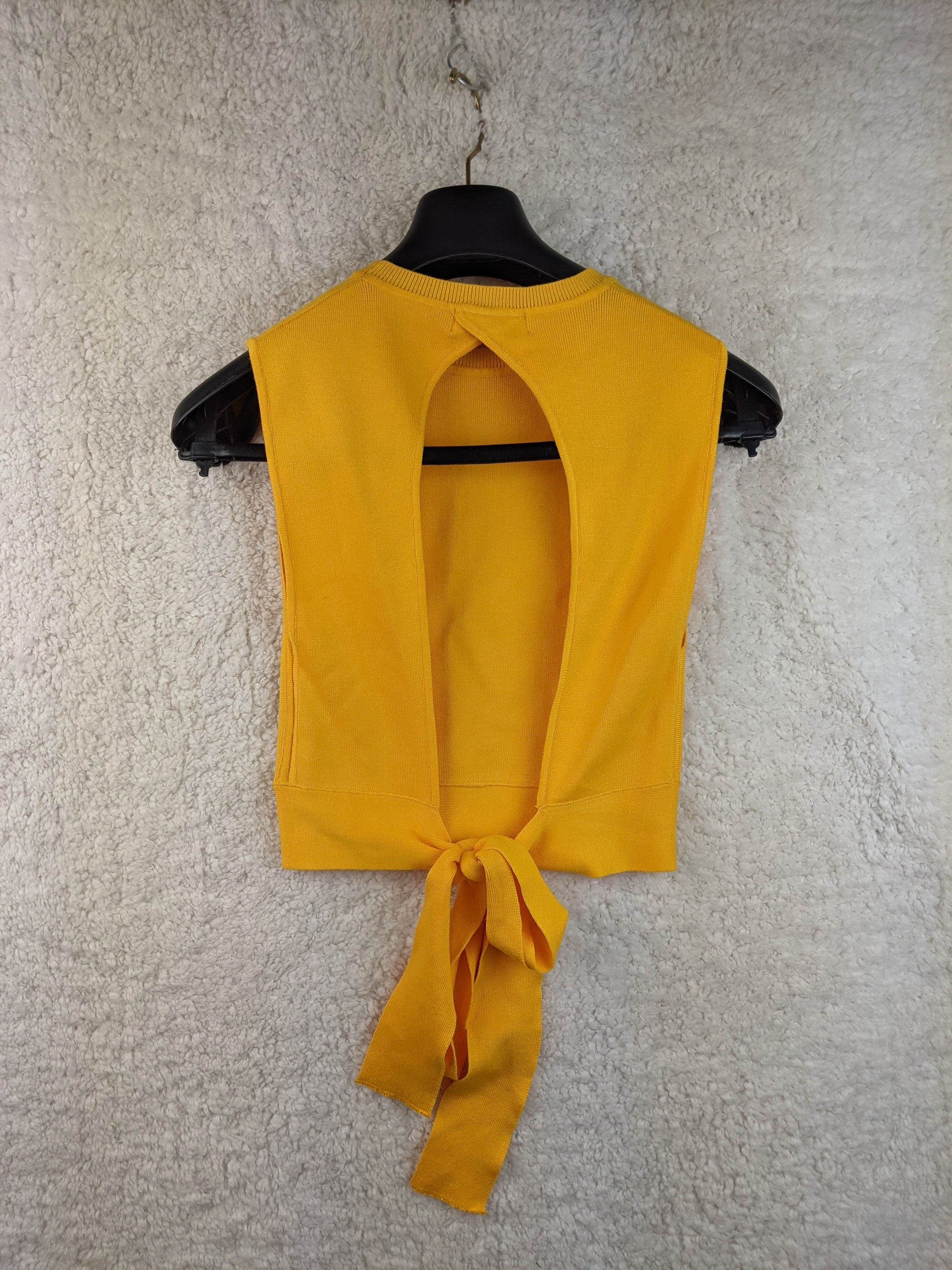 Yellow sleeveless top with tie-back on hanger - back view