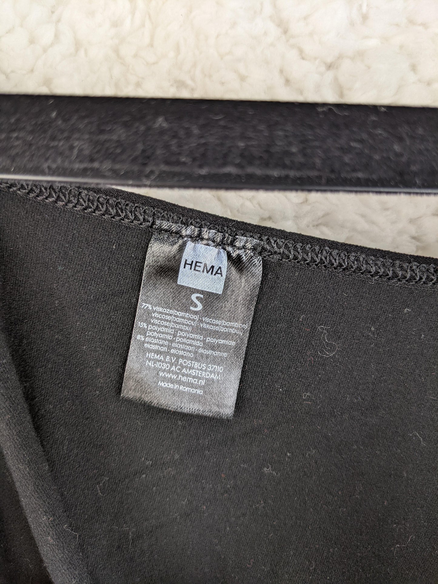 Close-up of HEMA label on black top showing size and material