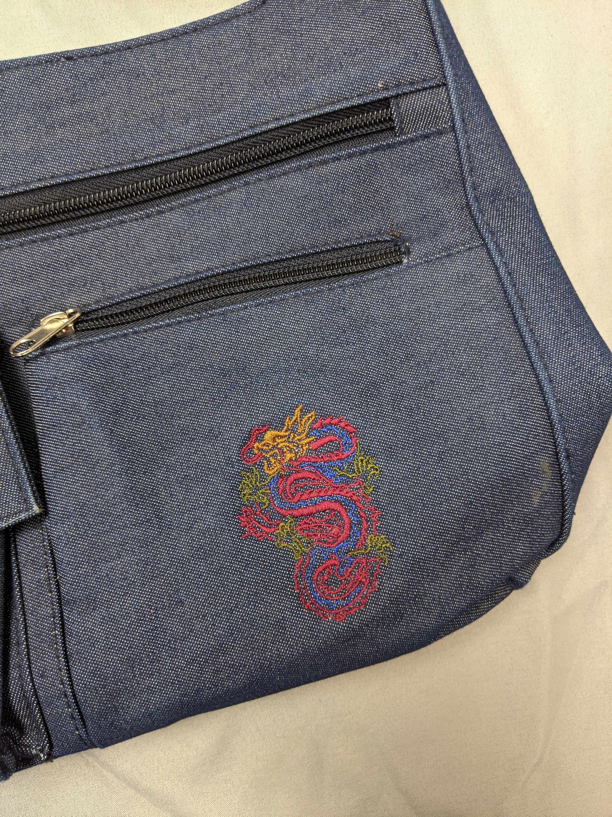 Close-up of dragon embroidery on blue denim bag.