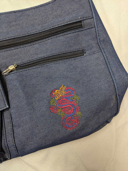 Close-up of dragon embroidery on blue denim bag.