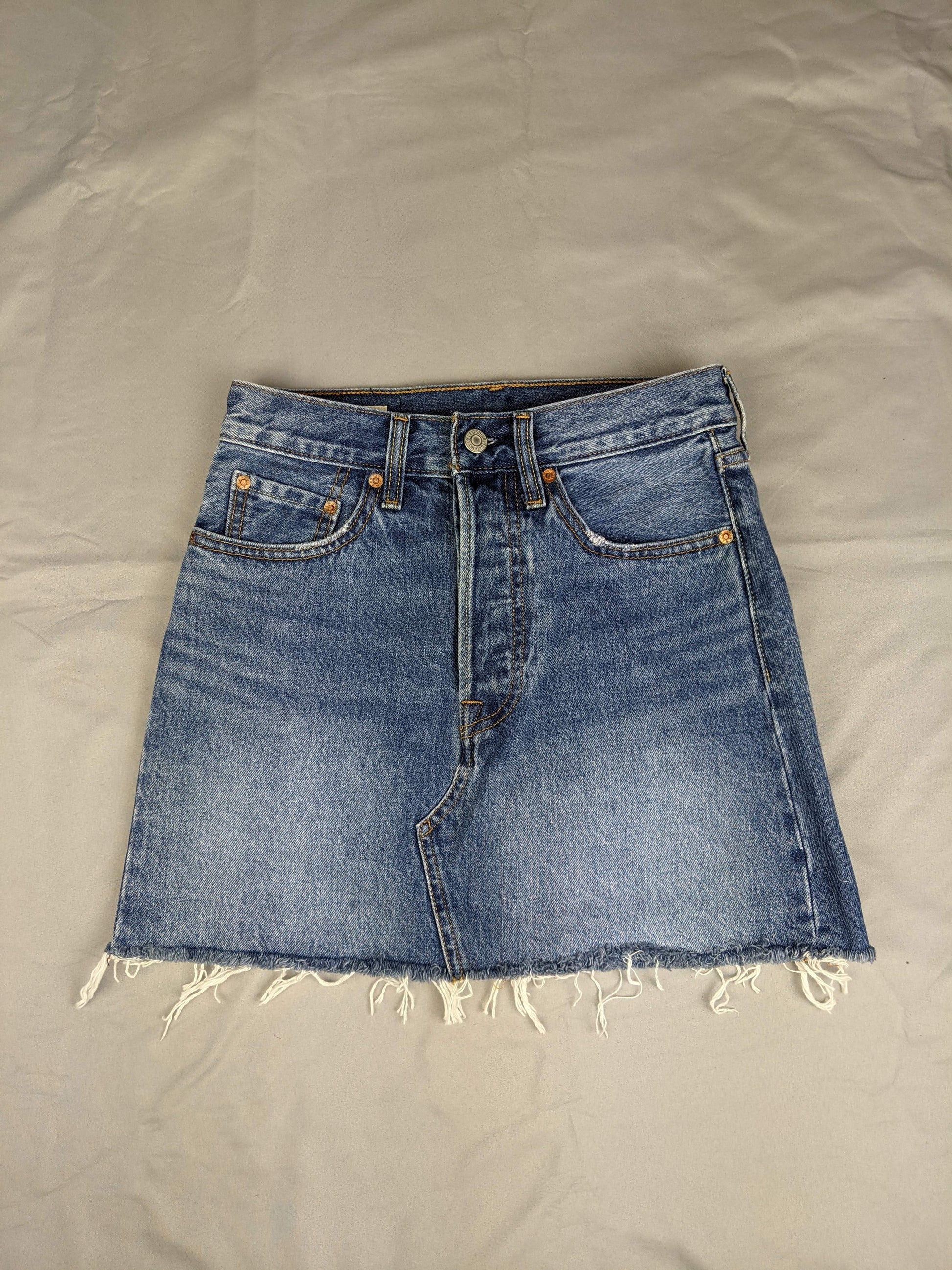Front view of blue denim skirt with raw hem